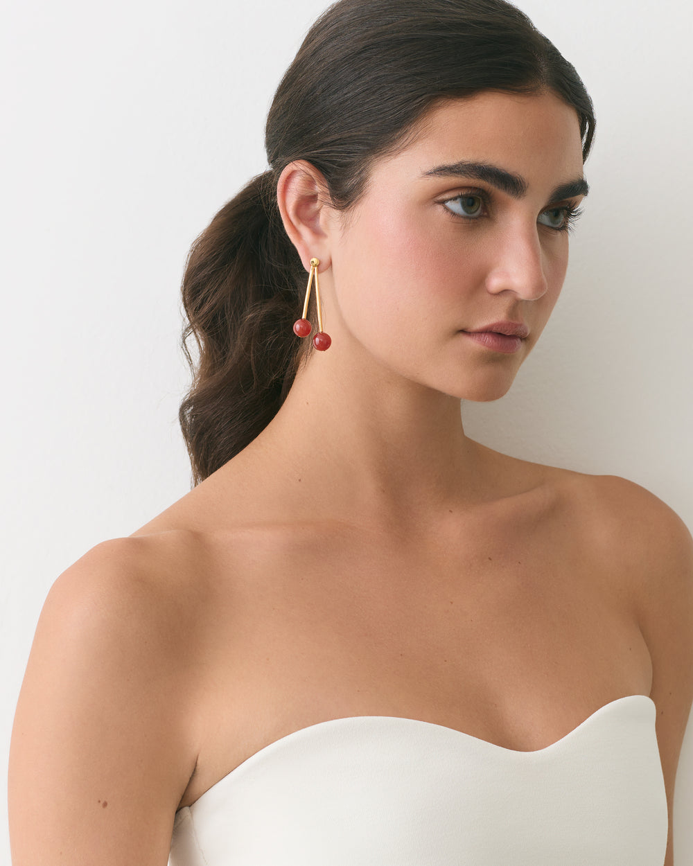 Person wearing drop earrings and strapless top looking to the side.