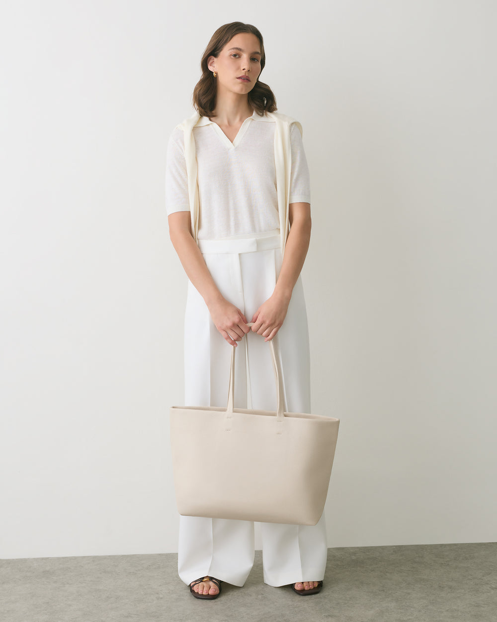 Person standing with a shoulder bag and hands in front