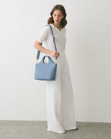 Person in outfit with wide-leg pants holds a shoulder bag.