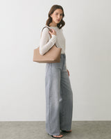 Person in sweater and wide-leg jeans carrying handbag on shoulder