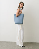Person wearing a large bag over their shoulder, wearing a long dress.