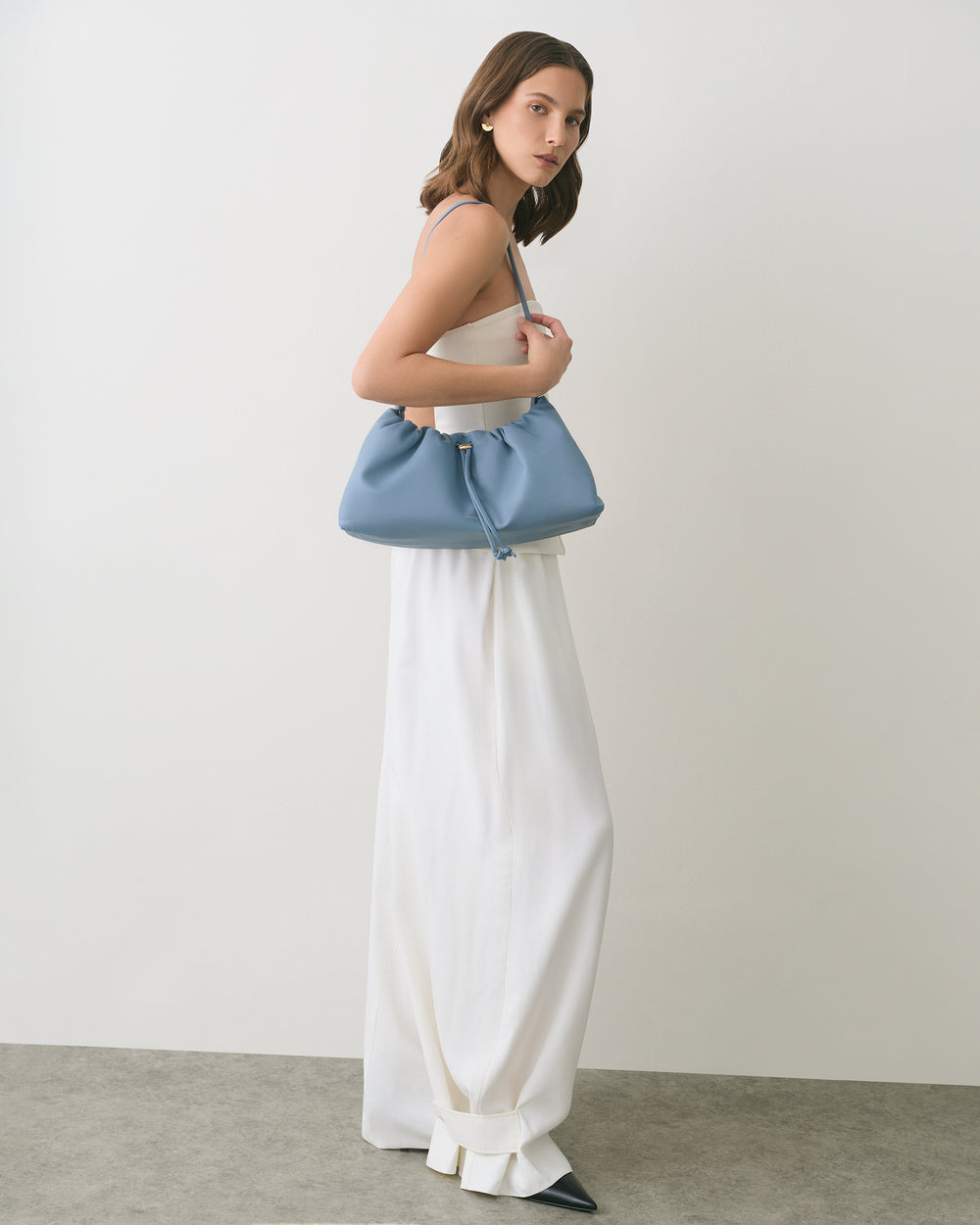 Person in a sleeveless top and long skirt holding a handbag.