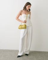 Person wearing a strapless top and wide pants, holding a small shoulder bag.
