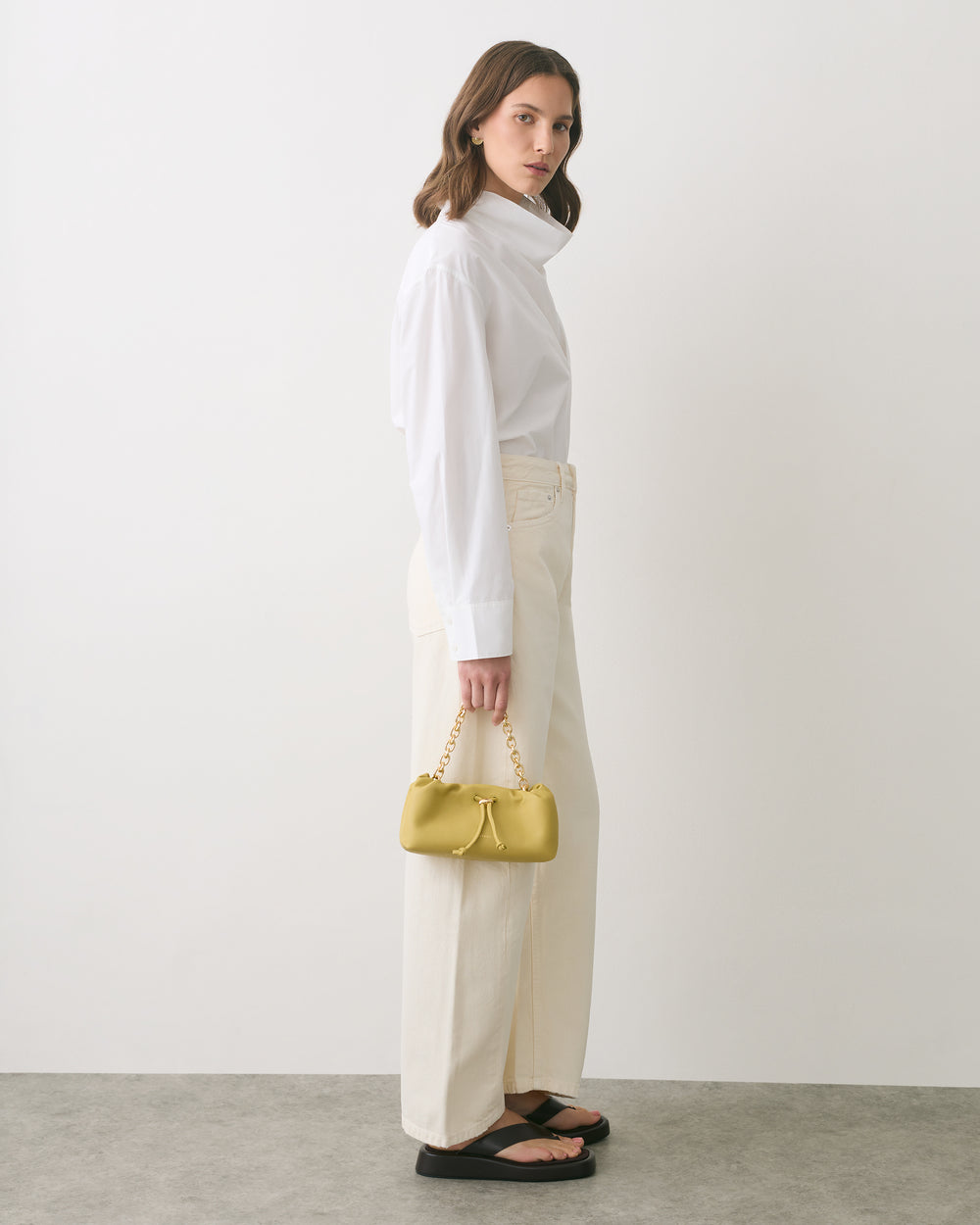 Person in long-sleeved shirt and pants holding small handbag.