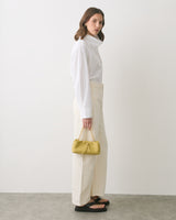 Person in long-sleeved shirt and pants holding small handbag.