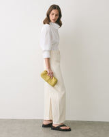 Person wearing long pants and holding a small clutch, standing sideways.