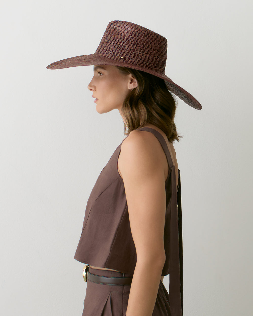 Person wearing a wide-brimmed hat and sleeveless top.