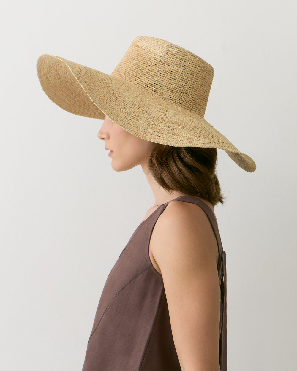 Person wearing a wide-brimmed hat and sleeveless top, looking sideways.