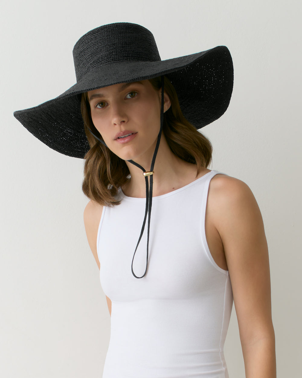 Person wearing wide-brimmed hat and sleeveless top.
