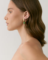 Person wearing a hoop earring with a green bead, shown in profile.