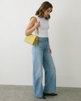 Person in sleeveless top and jeans holding a shoulder bag