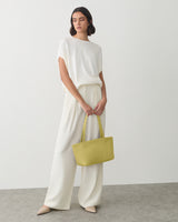 Person standing in wide-leg pants holding a tote bag