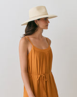 Woman in a sleeveless dress and wide-brim hat looking to the side.