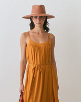 Woman in dress and hat holding a bag.