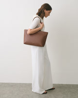 Person in white outfit holding a large handbag over shoulder.