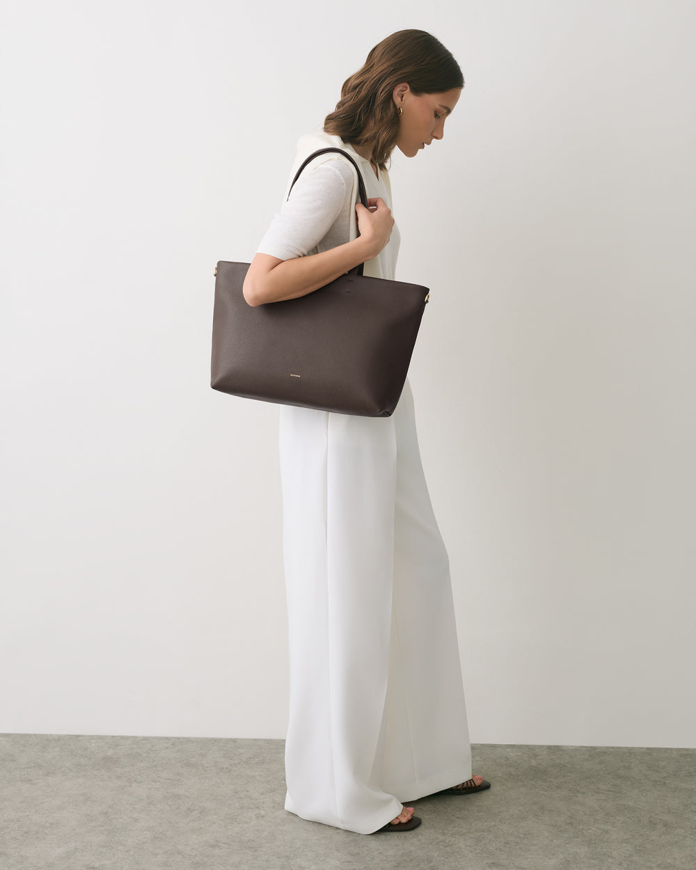 Person in white outfit carrying a large handbag.