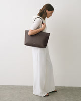 Person in white outfit carrying a large handbag.