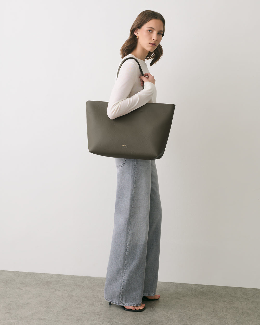 Person wearing long pants and carrying a large tote bag.