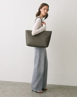 Person wearing long pants and carrying a large tote bag.