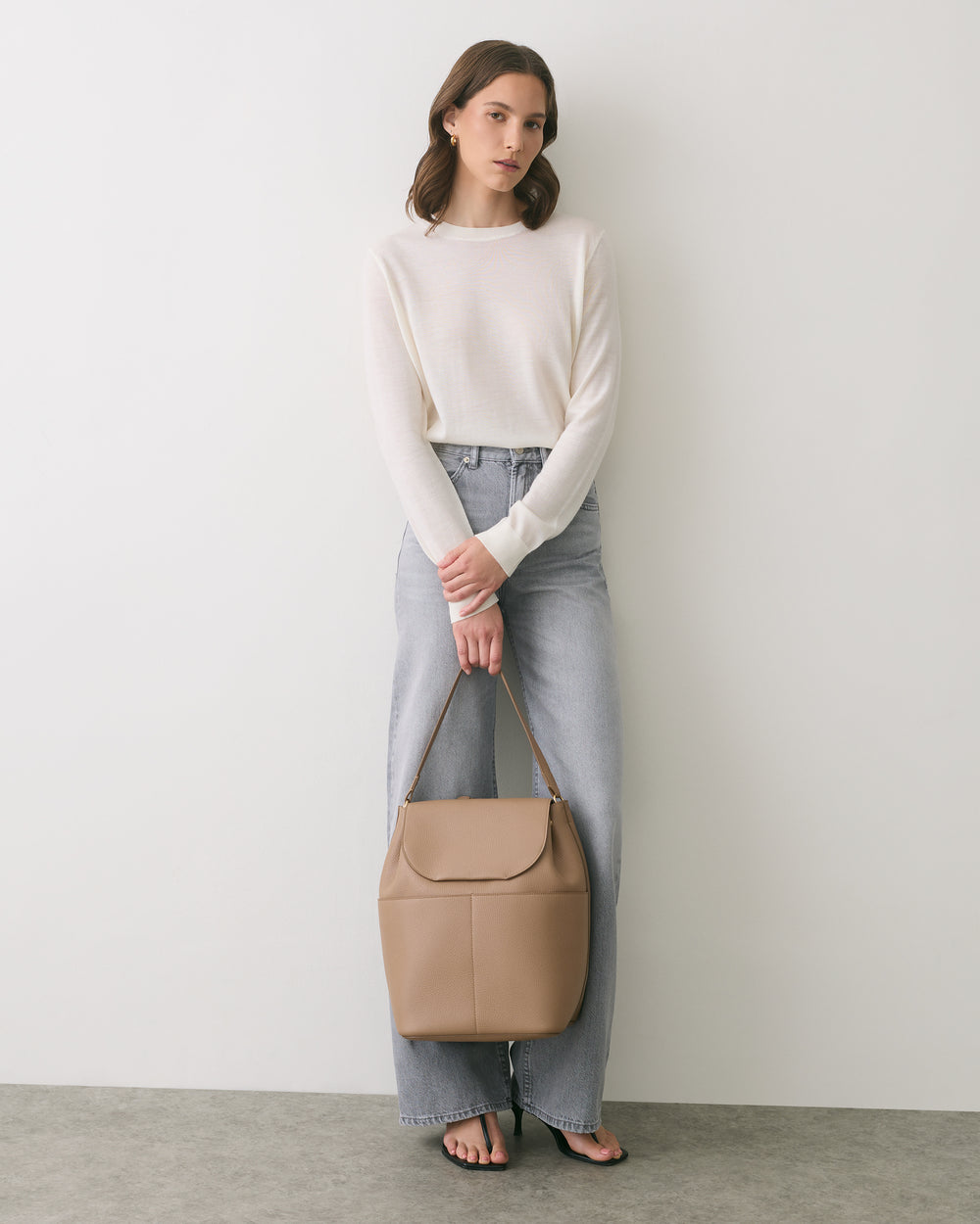 Person in casual outfit holding a handbag.