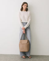 Person in casual outfit holding a handbag.