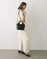 Person in profile with croc-embossed bag, wearing long pants and heeled shoes.