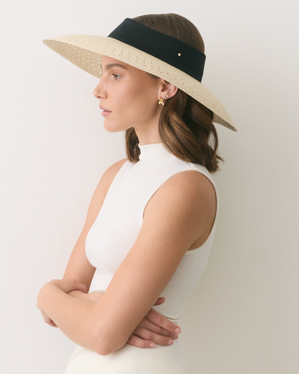 Person wearing a sleeveless top and wide-brimmed hat, facing sideways.