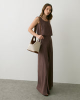 Person wearing sleeveless top and wide pants, holding a two-tone bag.