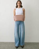 Person holding a round bag, wearing a sleeveless top and wide-leg jeans.