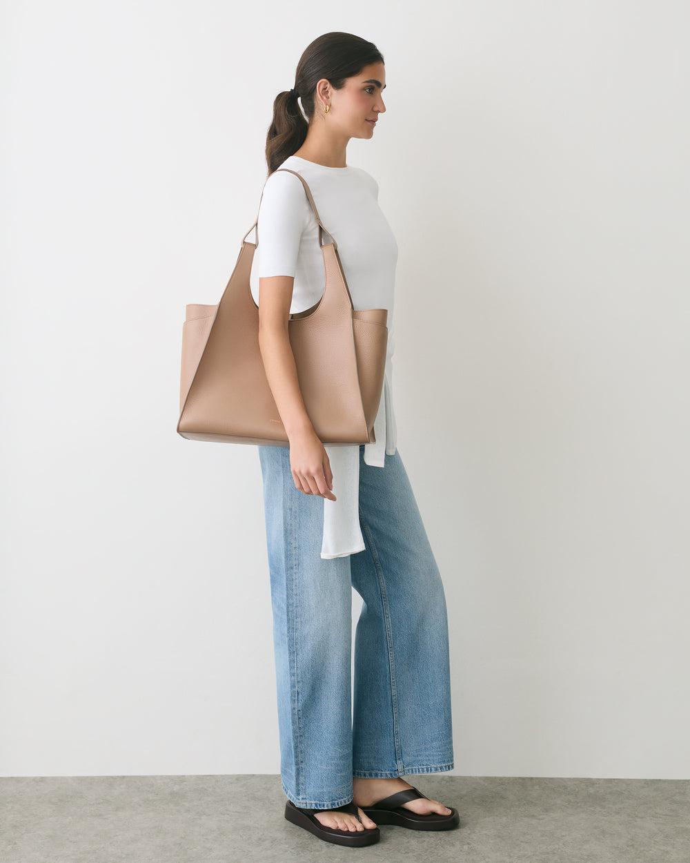 Person in casual outfit with shoulder bag facing sideways.
