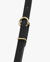 Close-up of a textured strap with gold metal buckle and ring.