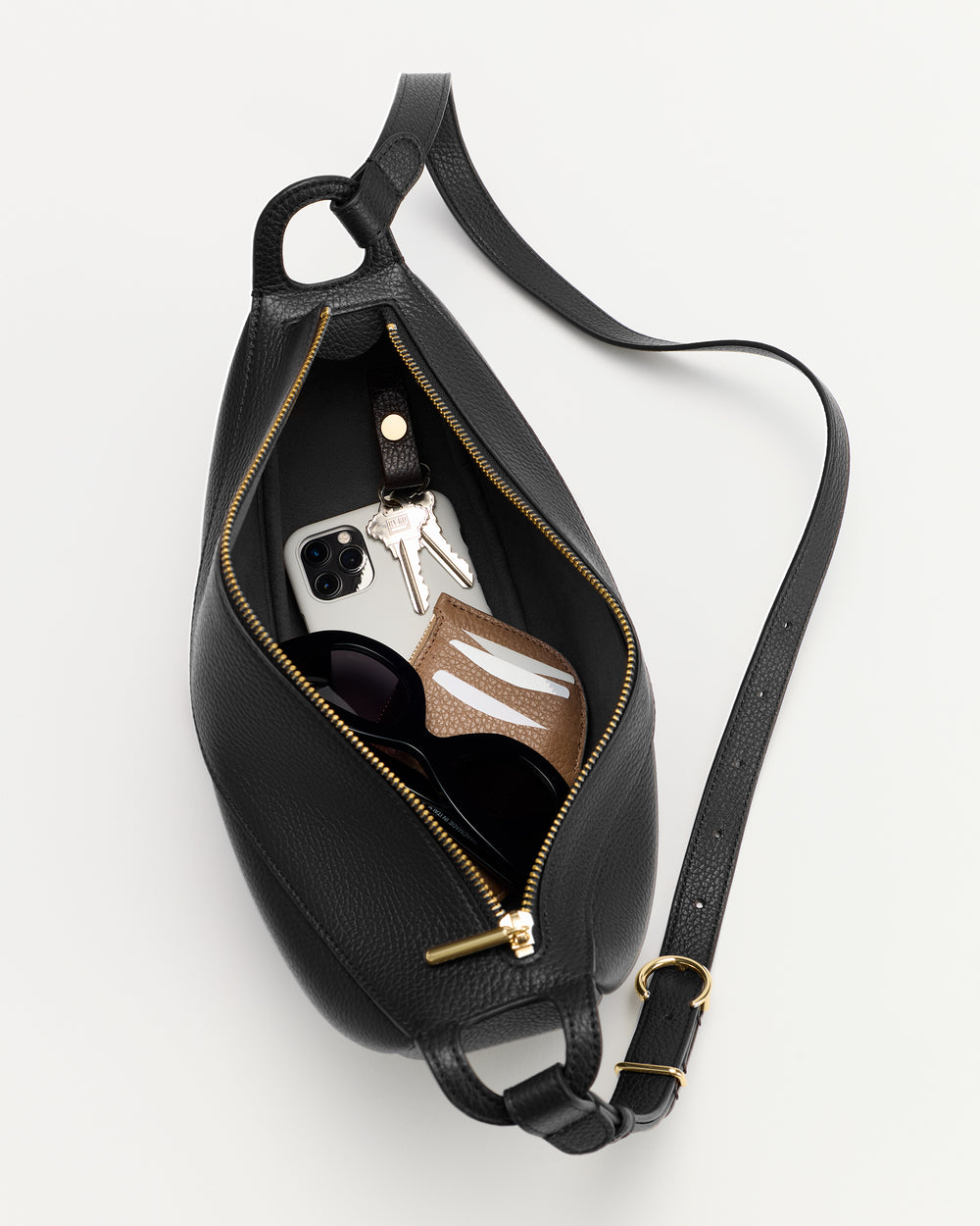 Belt bag open with keys, phone, and small pouch inside.