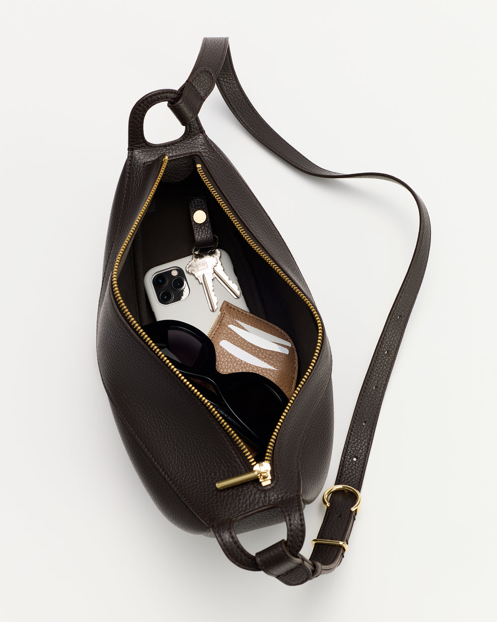 Open belt bag with phone, keys, sunglasses, and wallet inside.