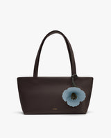 Tote bag with floral charm on handle.