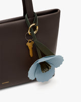 Handbag with decorative flower and keychain attached.
