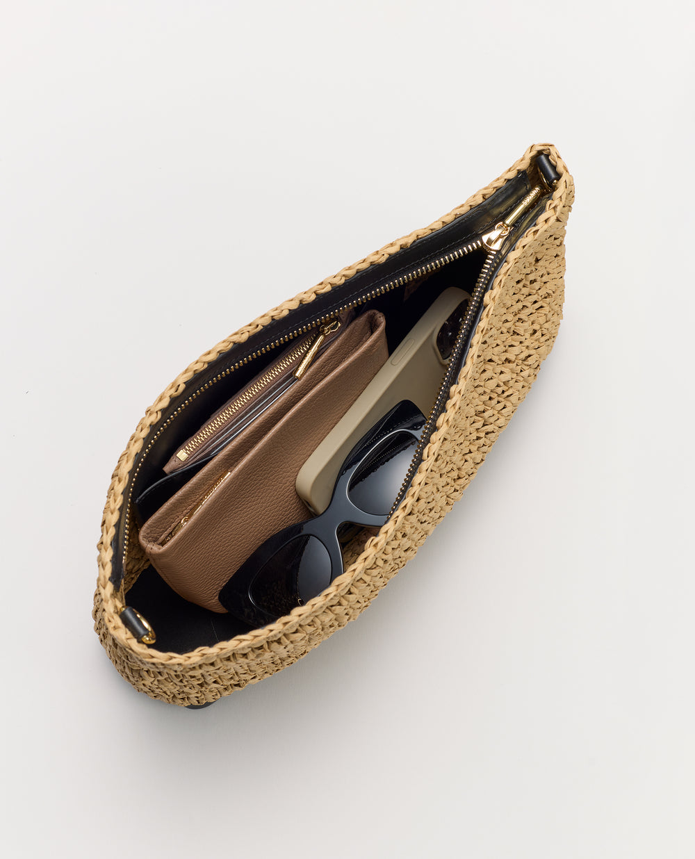Open woven bag with wallet, phone, sunglasses inside.