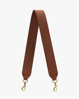 Bag strap with metal clips at both ends against plain background.