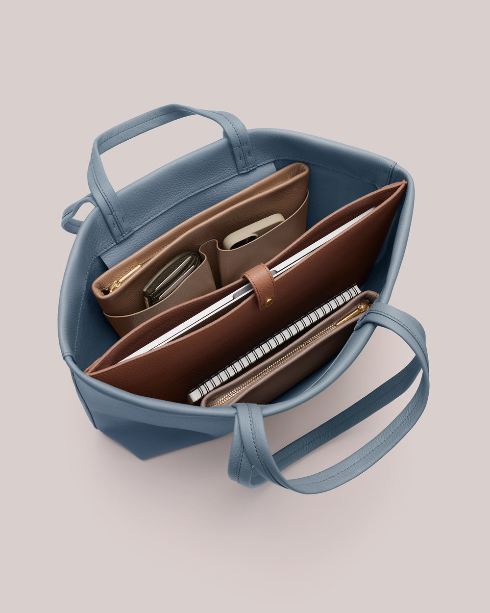 Open bag with notebooks, folders, and small items organized inside.