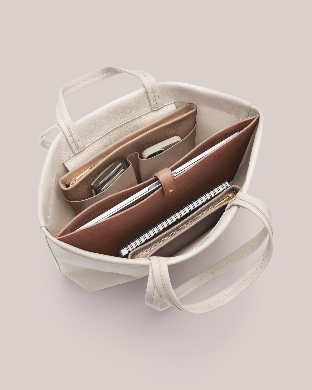 Open handbag showing organized items like a notebook and tablet inside.