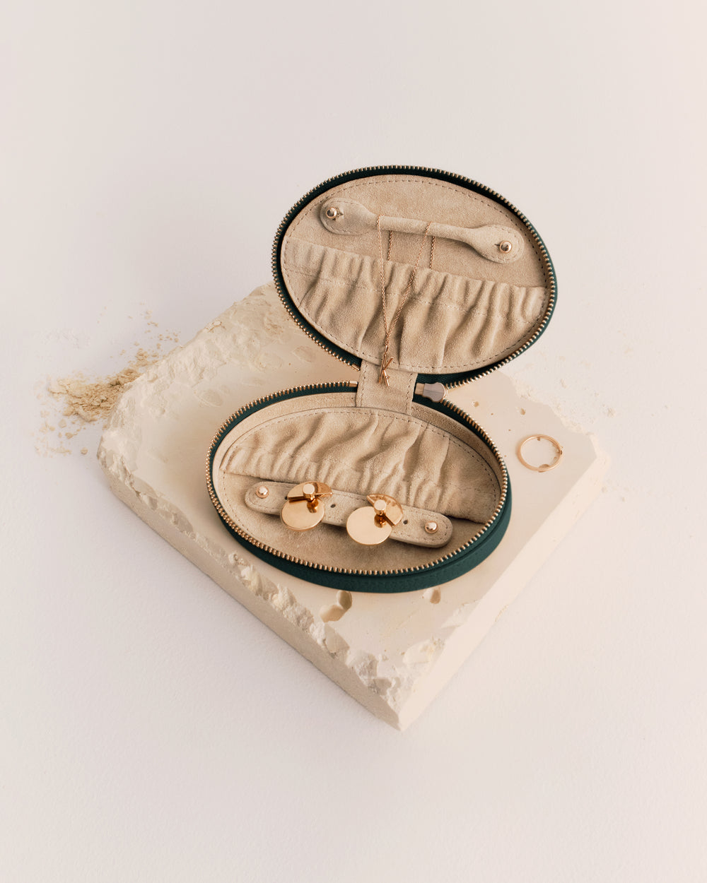 Oval jewelry case open on textured surface with rings inside