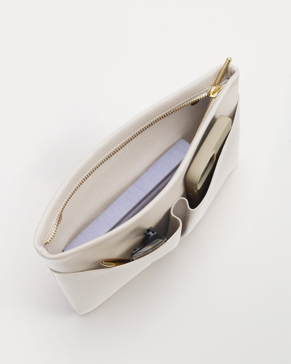 Open handbag with a phone, notebook, and pen inside.