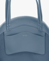 Close-up of a handbag with two handles and a small front pocket.