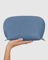 Hand holding a large pouch with a zipper on top.