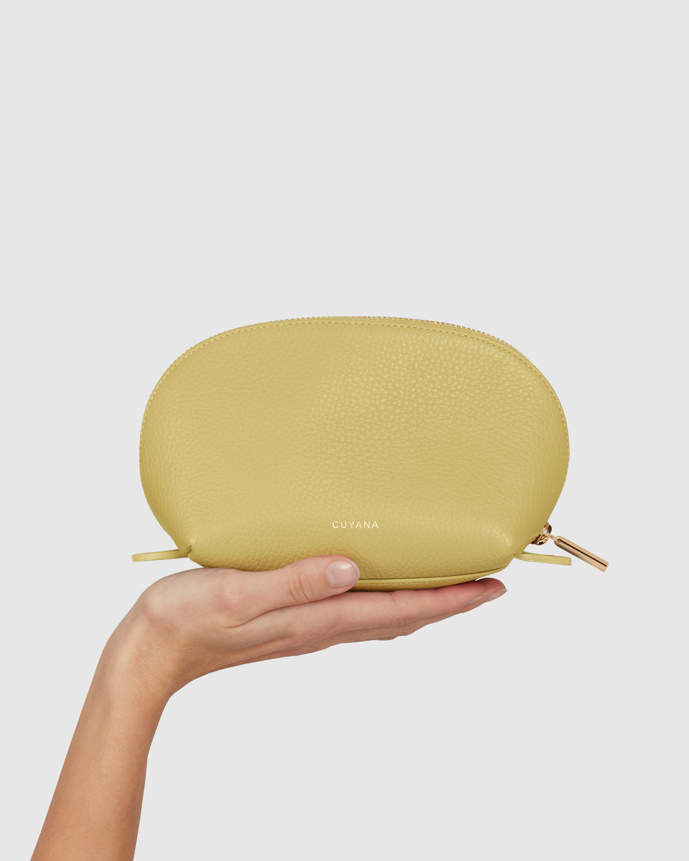 Hand holding a small oval handbag with zipper.