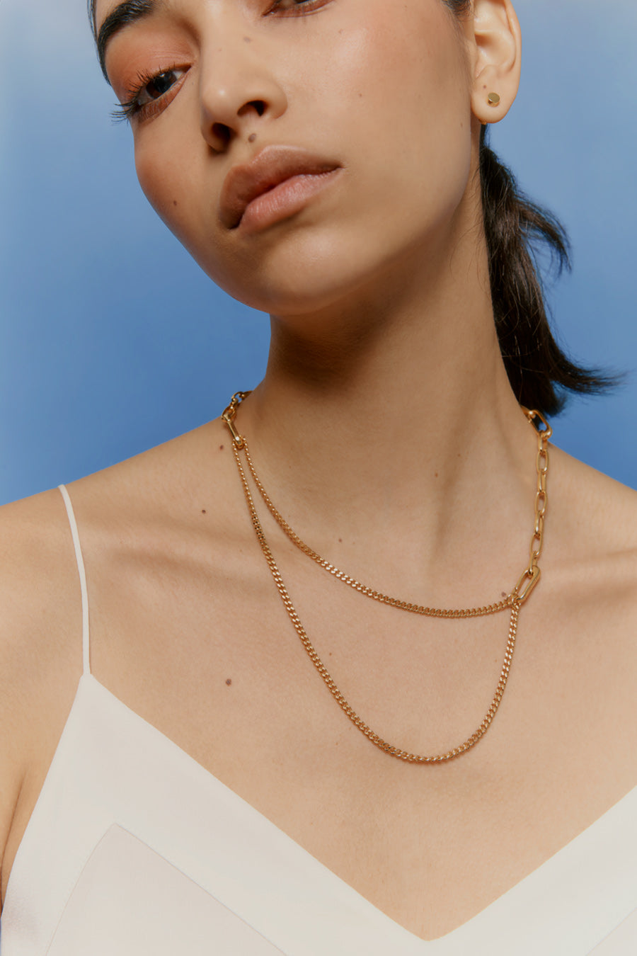 Close-up of a woman wearing a layered necklace and a top with thin straps.