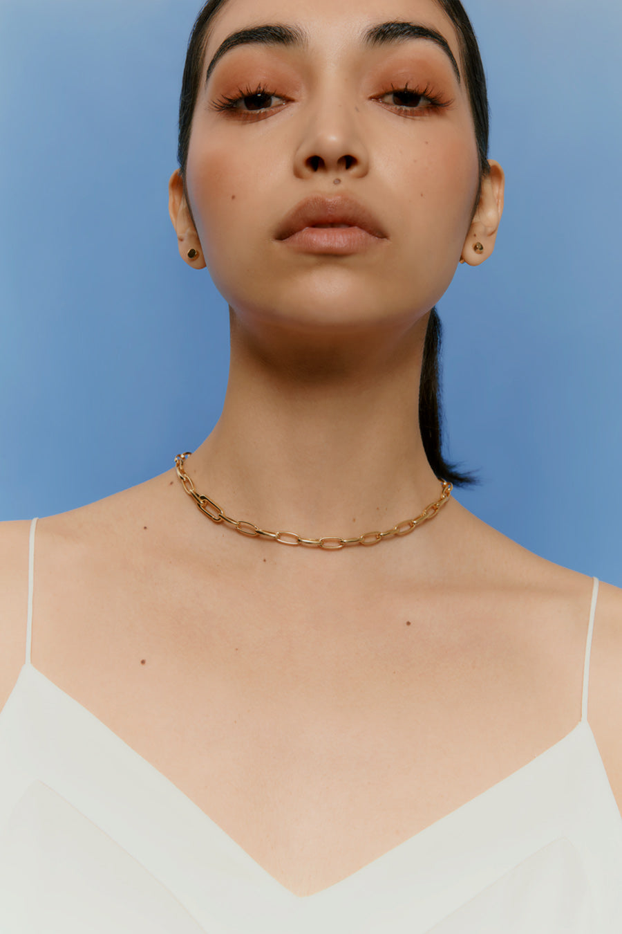 Close-up portrait of a woman wearing a necklace, looking upwards.