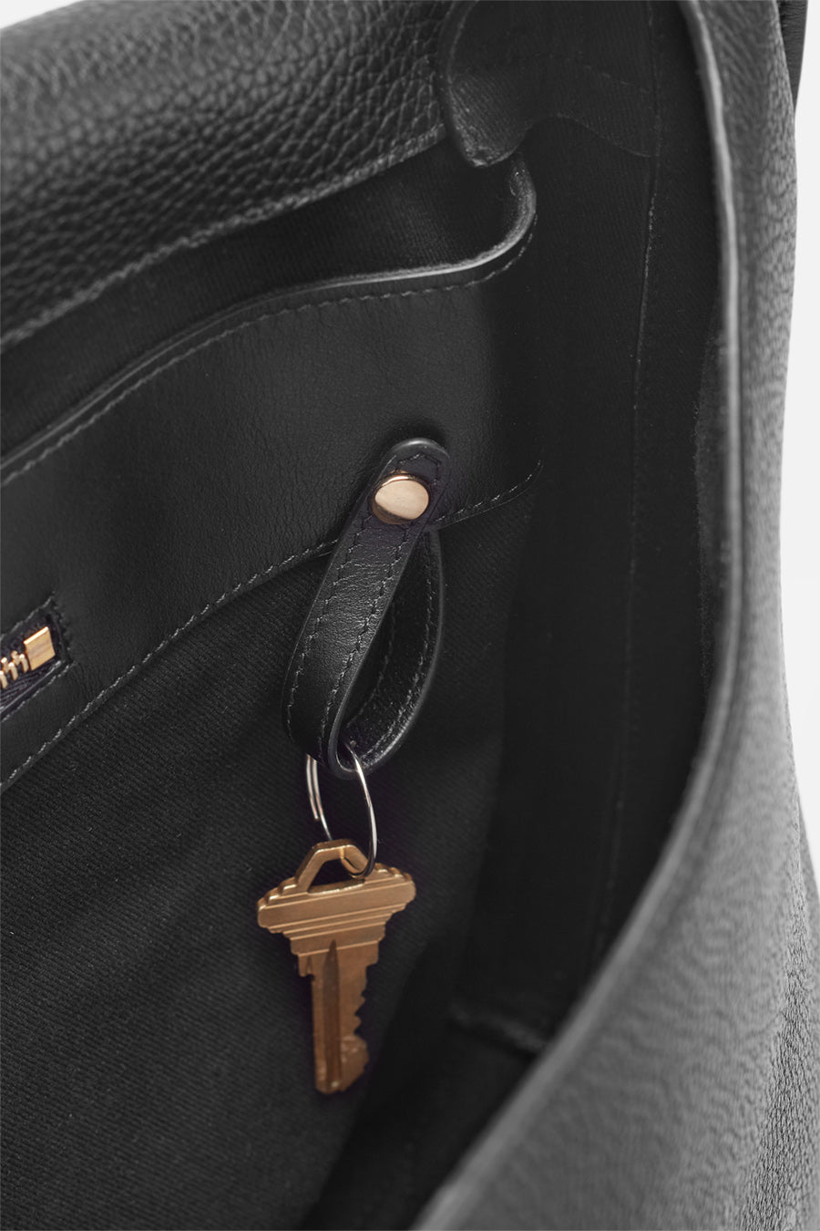 Close-up of a key hanging inside an open bag.