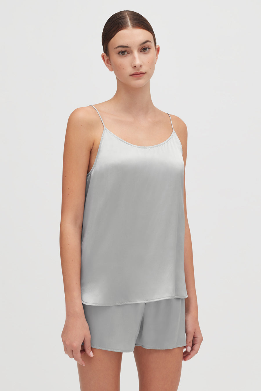 Woman in sleeveless top and shorts standing straight.