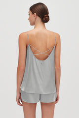 Woman wearing a tank top with crisscross straps on the back standing.