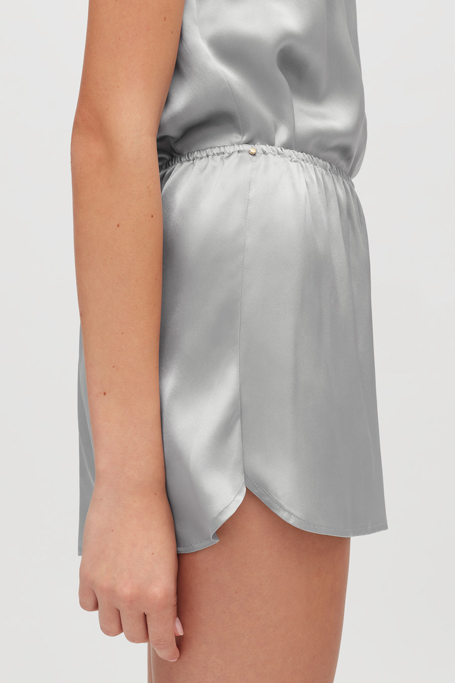 Woman wearing a sleeveless top and shorts, viewed from the side.